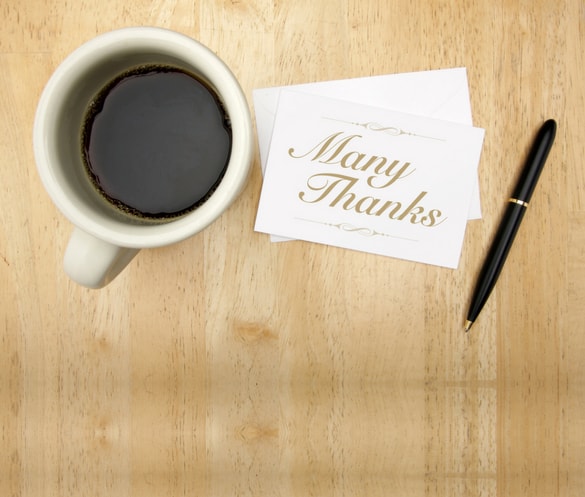 coffee in the table with a letter with Many thanks written and pen beside it